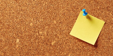 The corkboard with a pinned yellow sticky note and blue pushpin for reminders