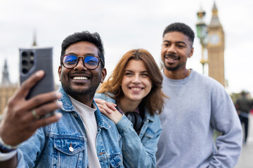Smiling friends taking a selfie in Westminster London with Big Ben