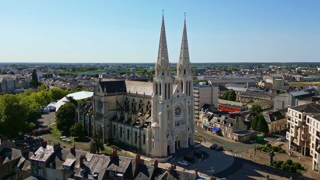 Saint Andrew Church in Chateauroux with city buildings surrounding and spires reaching skyward, aerial medium orbit establish