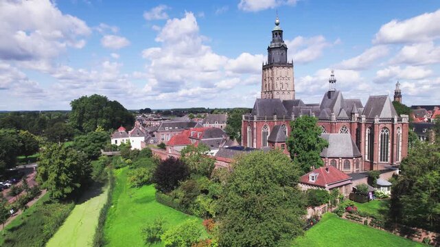 Community garden of medieval town Zutphen, The Netherlands, in the foreground with Walburgiskerk church tower rising above behind historic city wall against a blue sky. Aerial picturesque Dutch city