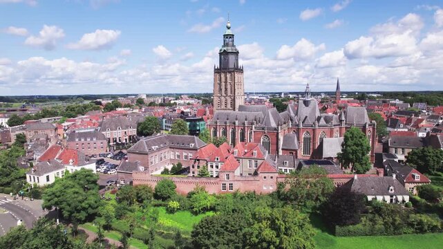 Medieval town Zutphen, The Netherlands, with Walburgis kerk church tower rising above historic city wall against a blue sky. Aerial approach of picturesque Dutch city