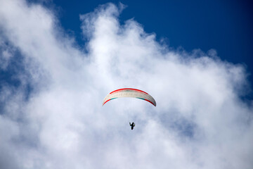 A man with a paraglider in front of a blue sky.
