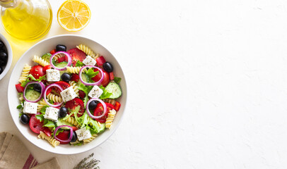 Greek pasta salad with feta cheese, tomatoes, onion, cucumbers, peppers and olives. Healthy eating. Vegetarian food.