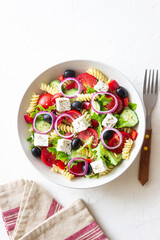 Greek pasta salad with feta cheese, tomatoes, onion, cucumbers, peppers and olives. Healthy eating. Vegetarian food.