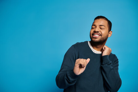 Young man in casual blue outfit joyfully enjoying his time in a studio setting