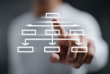 Blurred person pointing at a glowing flowchart with boxes and arrows against a dark background