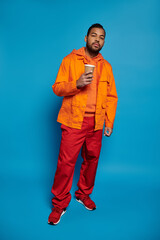Fototapeta premium Vibrant young man in urban fashion poses confidently in stylish orange attire