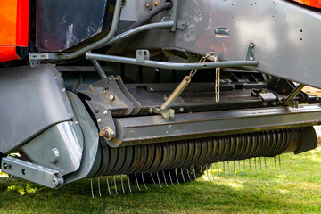 Close-up of round baler with pickup and metal tines for hay collection, technical detail of modern agricultural machine used during harvest.