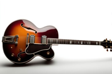 Fototapeta premium Archtop guitar with sunburst finish and elegant curves laying horizontally on a white surface, highlighting its details