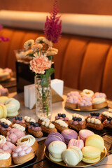 Colorful macaroons and pastries displayed elegantly in a stylish cafe setting with fresh flowers on the table