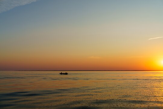 A silhouette of a fishing boat on the Baltic Sea at sunset, with golden hues reflecting on the water. This serene scene embodies coastal life and adventure, ideal for travel themes.
