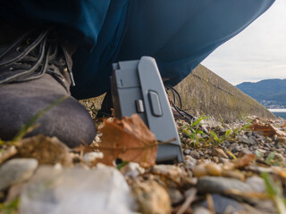Aerial landscape of DJI drone battery on ground by boots fall leaves in Italian Alps Lombardy