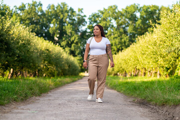 Fototapeta premium Curvy female with tattoo arm enjoying walk along pathway