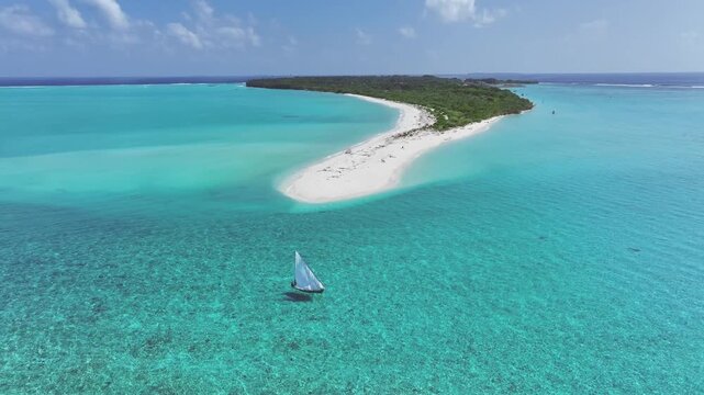 Aerial view of a sailboat sailing on the turquoise waters near the white sandy beach of Billefahi island contrasting with the deep blue sea, Billefahi, Shaviyani Atoll, Maldives.