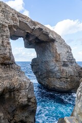 Natural rock arch over blue sea.