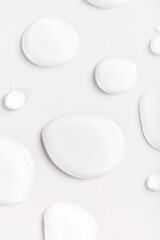 round drops of transparent gel serum oil on a light background close-up