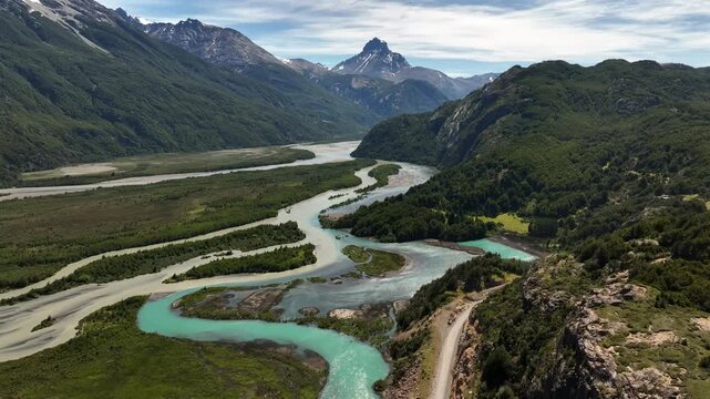 Aerial view of winding turquoise river through lush green valleys, contrasted by rugged mountains and a lonely road, Carretera Austral, Villa Cerro Castillo, Ays&eacute;n, Chile.
