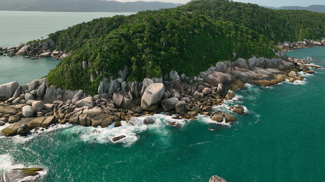 Aerial view of a tropical island where emerald waters meet rugged, rocky shores and verdant, dense forests, showcasing nature's raw beauty, Paraty, State of Rio de Janeiro, Brazil.