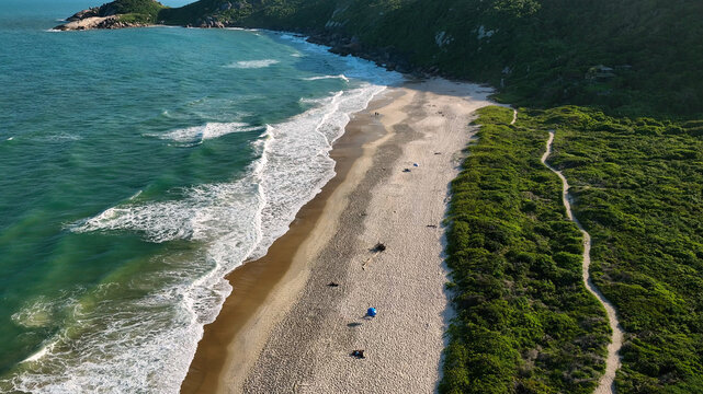 Aerial view of the coastline where the turquoise sea meets the soft, sandy beach, bordered by lush green vegetation, Paraty, State of Rio de Janeiro, Brazil.