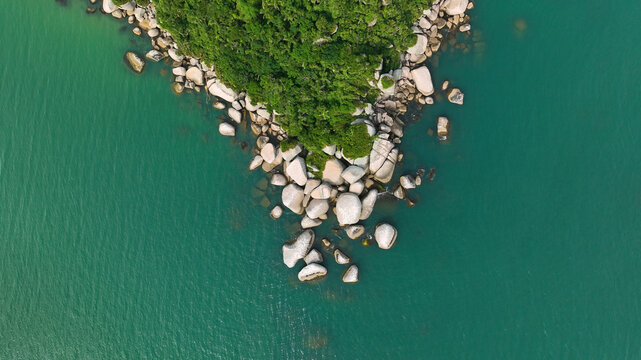 Aerial view of the rocky coastline, where the verdant green foliage meets the turquoise waters, creating a stunning contrast of colors and textures, Paraty, State of Rio de Janeiro, Brazil.