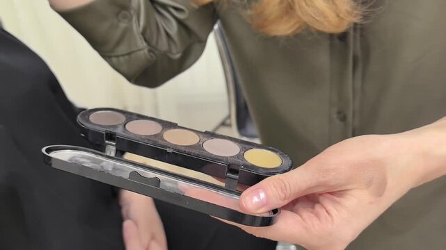 Watch as a skilled makeup artist expertly applies highlighter using a professional palette. This tutorial captures the artistry involved in creating a stunning look, showcasing techniques and tips.
