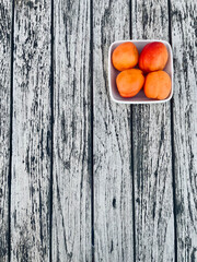 Fresh assorted fruits in the foreground on an old rustic wooden table. The colorful seasonal fruit arrangement creates a natural, healthy, and organic atmosphere
