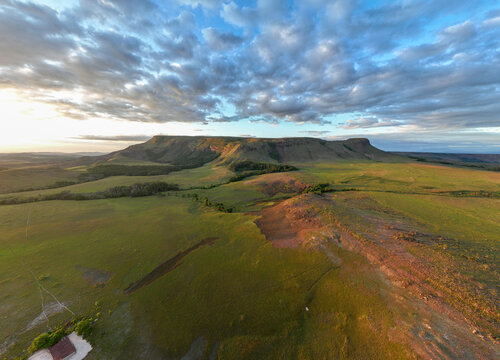 Aerial view of the tepui standing majestically against the horizon, its flat top a stark contrast to the surrounding green savannas, Chiricayen Tepui, Santa Elena de Uairen, Venezuela.