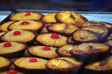 Assortment of golden pastries with red cherries, displayed on a tray.