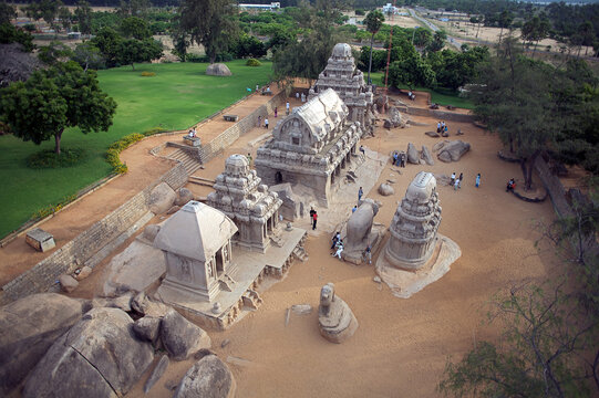 Mahabalipuram, India - 17 September 2006: Aerial view of Pancha Rathas monuments, ancient stone temples bathed in warm sunlight, surrounded by lush green lawns and trees.