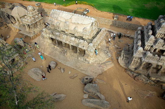 Mahabalipuram, India - 17 September 2006: Aerial view of the monolithic rock-cut architecture of the Pancha Rathas, bathed in warm sunlight against the backdrop of lush greenery.