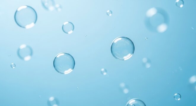 Transparent spherical bubbles of varying sizes float against a soft blue background Some bubbles are sharply defined showing clear reflections while others are gently blurred - Powered by Adobe