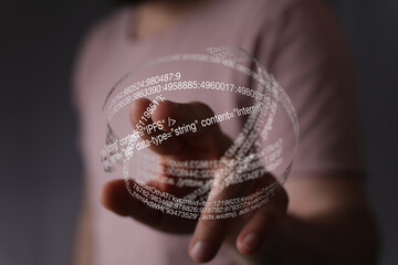 Hand interacting with a futuristic digital sphere filled with code.