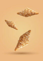 Three Almond Croissants of different sizes arranged on a cream background.