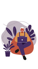 Senior man working remotely on a laptop, comfortably seated on a beanbag chair surrounded by plants, illustrating flexible work and modern lifestyle.