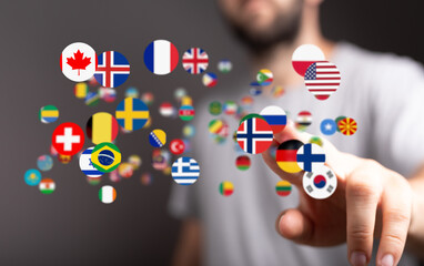 A man interacts with a digital display of various national flags, symbolizing global communication...