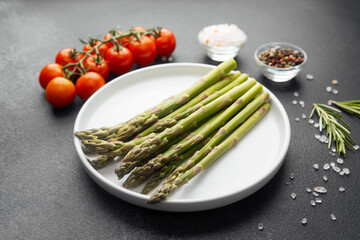 Asparagus with tomatoes, herbs and spices on dark
