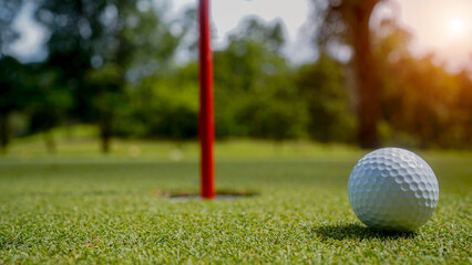 Golf ball is on a green lawn in a beautiful golf course with morning sunshine.