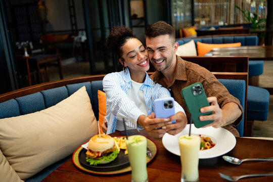 Young couple sharing dining experience at tropical restaurant, engaging with their online followers