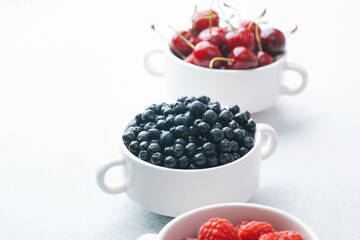 Bowls of raspberries, blueberries and cherries for fruit trio, diet or nutrition concept