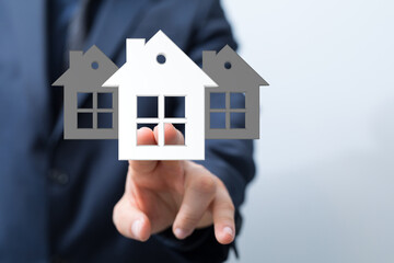Businessman showcasing house models, representing real estate investment, property management, or home buying.