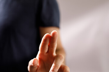 Obraz premium Close-up image of a person crossing their fingers, symbolizing hope, luck, or a wish. Perfect for concepts of optimism, good luck, and positive thinking.