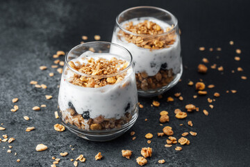 Parfaits with granola and yogurt in glass on dark  background