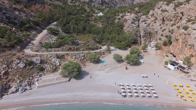 Aerial drone footage revealing the wild beauty of Achata Beach in Karpathos, moving from sea to shore