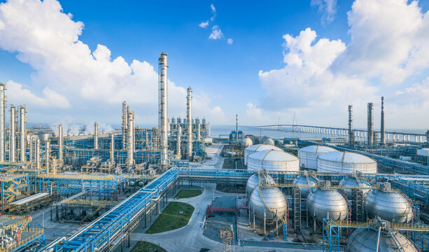 Panoramic view of oil refinery and chemical plant with complex pipelines, storage tanks and a bridge in the background.