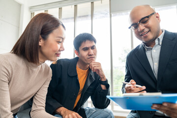 A young couple discusses life health and home insurance plans with an advisor ready to sign documents for future security and peace of mind. Meets with an insurance agent to review and sign policies