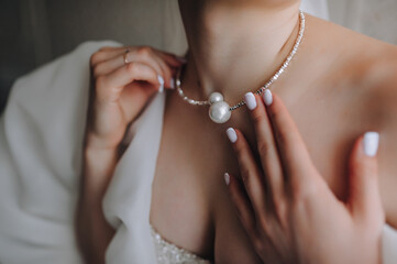Wedding photography, portrait of a beautiful young bride in a white dress with a pendant, pearls, necklace on her neck.