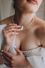 Wedding photography, close-up portrait of a beautiful young bride in a white dress with a pendant, pearls, necklace on her neck.