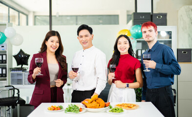 Happy business team raising glasses in celebration around office dinner table, showing corporate culture, team spirit, success, and joyful coworking lifestyle.