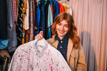 A Fashionable Young Woman Happily Holding a Colorful Shirt in a Clothing Store