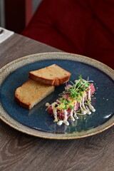 Served veal tartare with toasted bread in a modern style, elegantly plated in a restaurant setting. Close-up of the dish on the table, highlighting the texture of the meat and sophisticated presentati